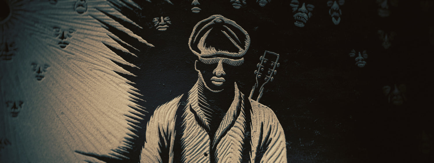 Linocut illustration of a person with a guitar against a dark background with faces. From the movie Sinners.
https://www.experienceperception.com/wp-content/uploads/banners/sinners-perception-02-uai-2880x1086.jpg